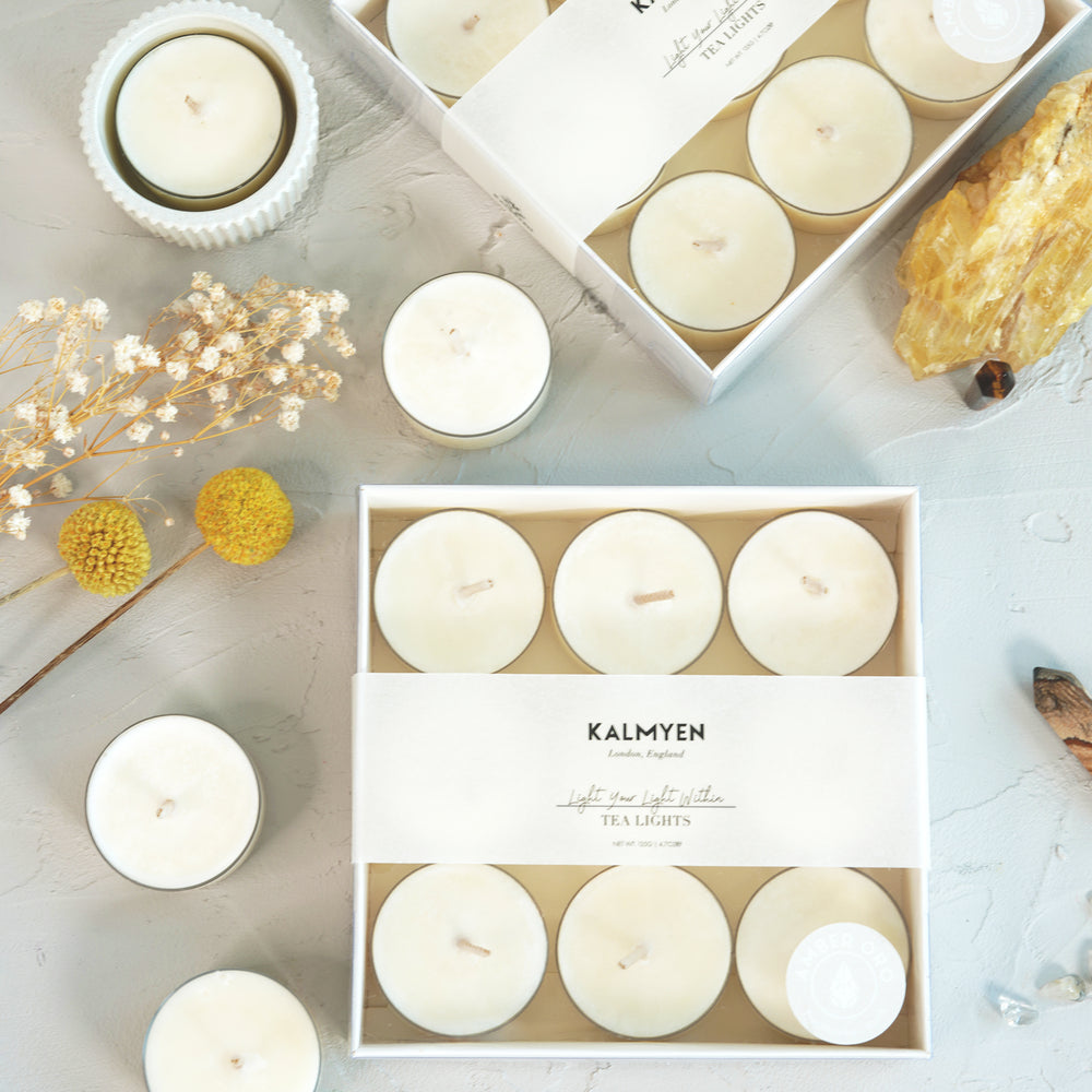 Image of amber oro tealight boxes with loose tealights and natural flowers in the background, accompanied by a large crystal and mini point tigers crystal.