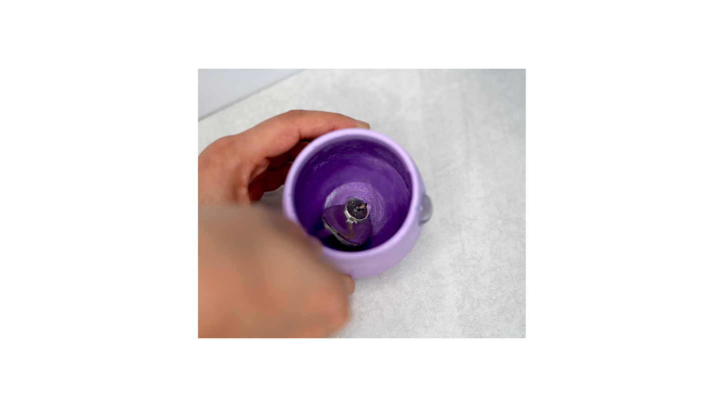 Luna Iris Jar showing a spoon being used to carefully removed the tabbed wick from inside the candle jar. 